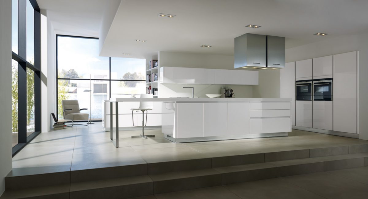 White handleless kitchen with a central island and built-in ovens.